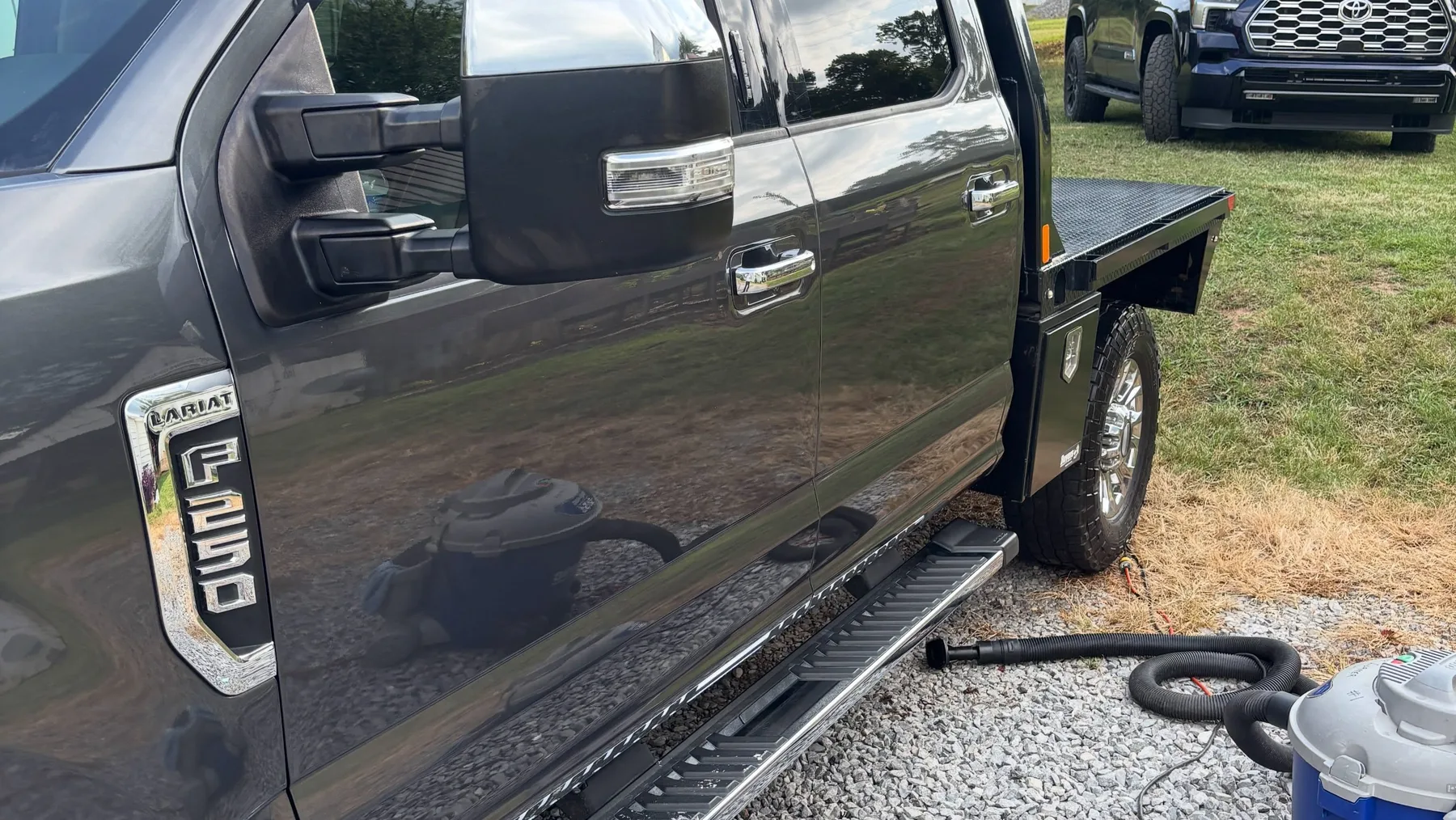Ford F-250 flatbed being detailed on site with a shop vacuum alongside