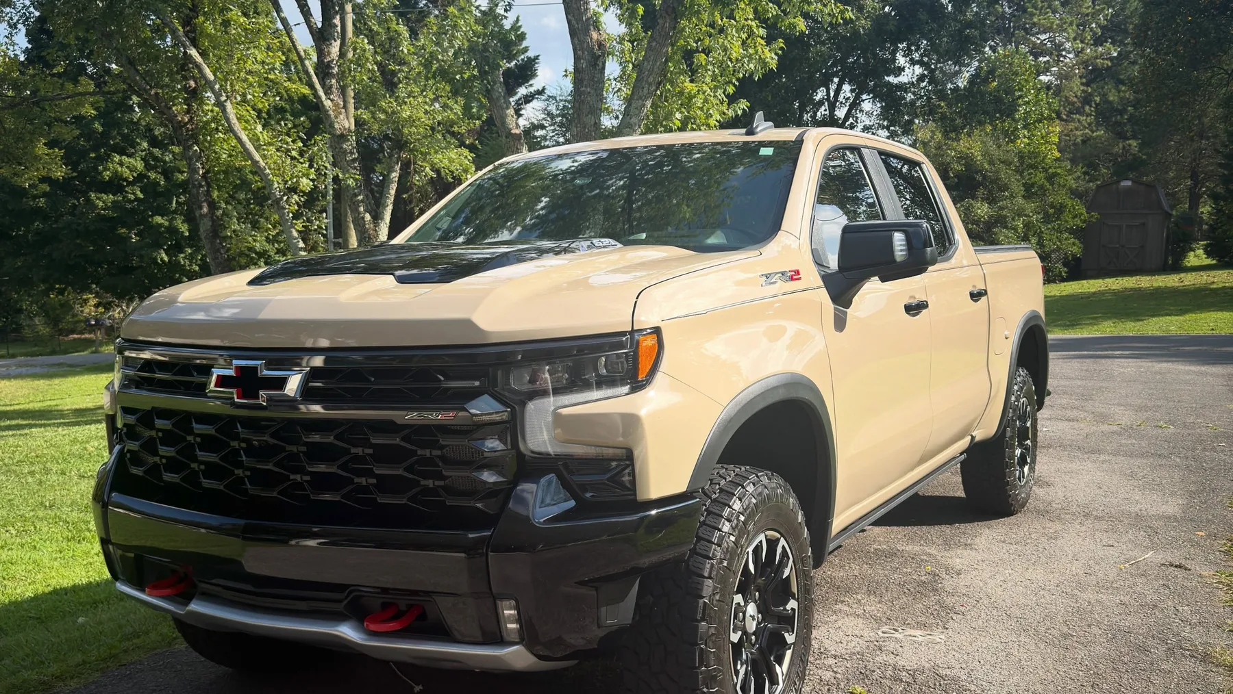 Desert sand Chevrolet Silverado ZR2 detailed and parked under trees