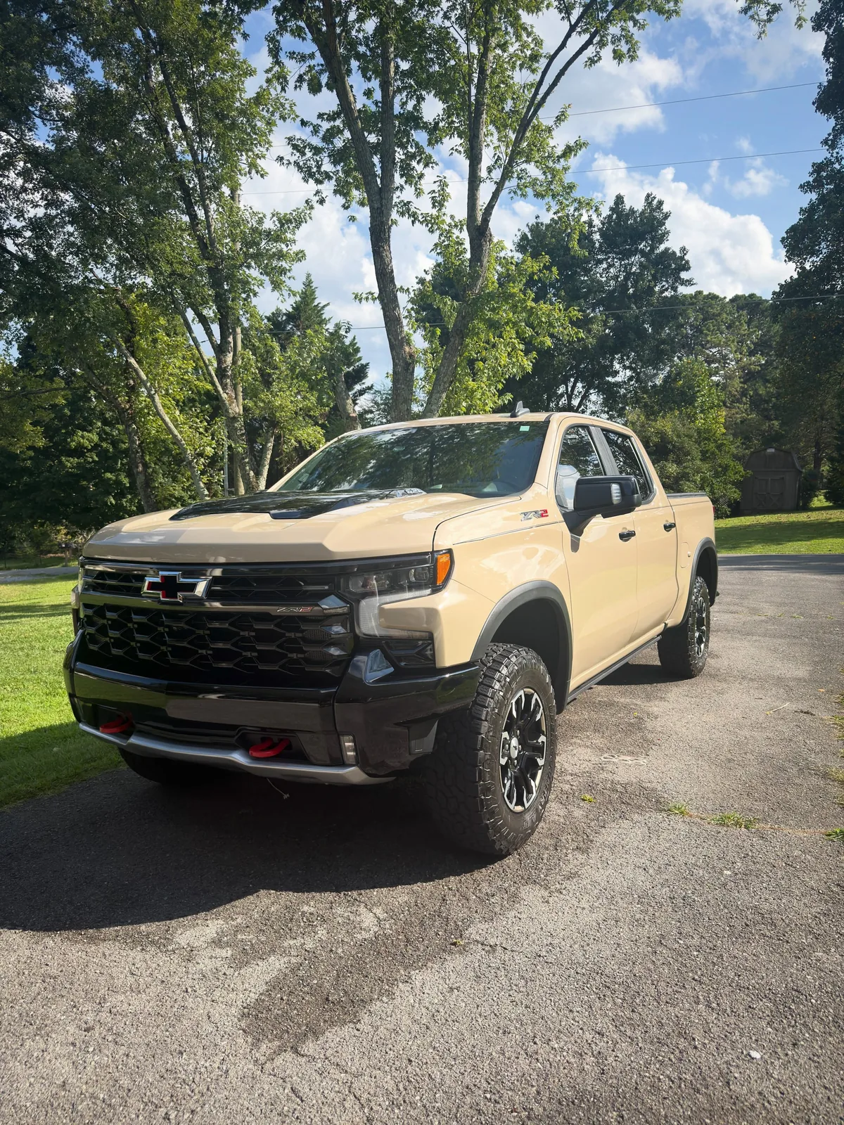 Desert sand Chevrolet Silverado ZR2 finished and parked under trees